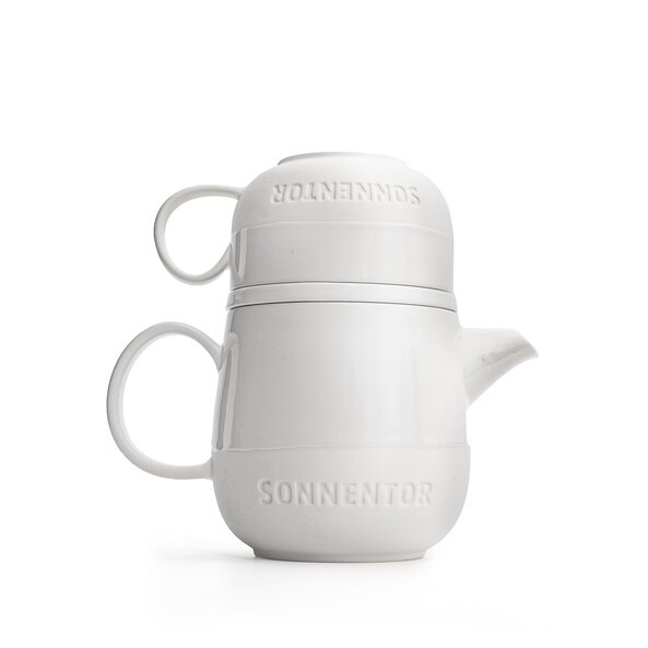 The set is made of white porcelain, the lower half is matt and contains the lettering "SONNENTOR". The cup sits upside down on the pot.